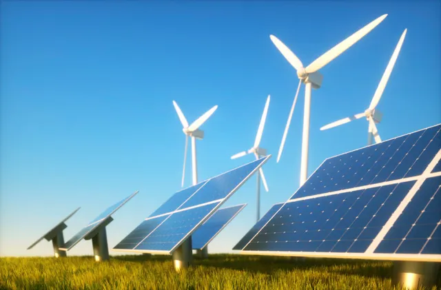 Paneles solares y aerogeneradores en un prado bajo un cielo despejado